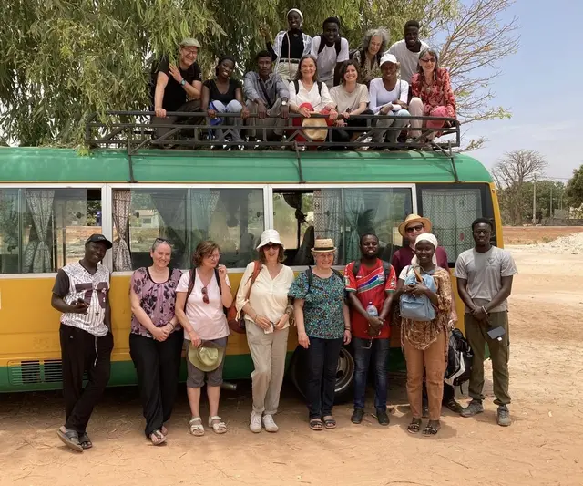 Das Foto zeigt die Reisegruppe (fast vollständig) und einige Lehrer*innenin Juffureh, der Heimat von Kunta Kinteh (aus dem Buch und Film "Roots"), einer Gedenkstätte für die nach Amerika verschleppten Sklav*innen aus Westafrika.
