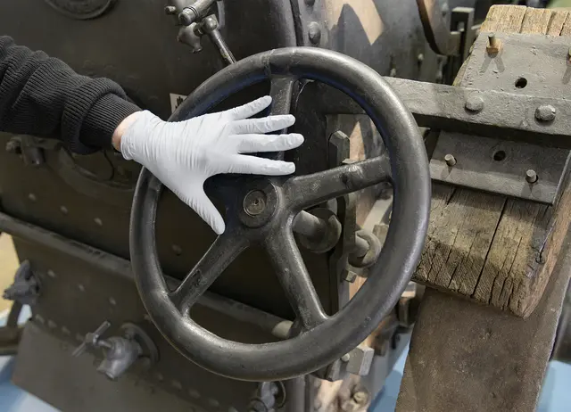 Eine Hand, die einen Handschuh trägt, ertastet eine historische Landmaschine im TECHNOSEUM | Foto: TECHNOSEUM, Klaus Luginsland