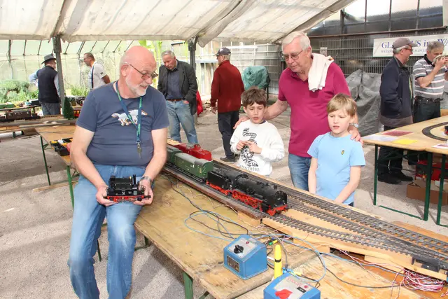 Gartenbahn-Experte Gerold Körner (links) erklärt Lorenz und Johann (rechts) sowie Opa Toni wie eine Gartenbahn funktioniert. 