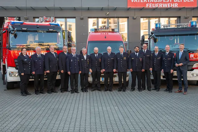 Gut gelaunt: Laudatoren und Geehrte posieren gemeinsam für ein Gruppenbild vor den aufgereihten Einsatzfahrzeugen.